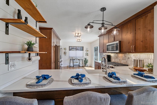 kitchen with open shelves, appliances with stainless steel finishes, a kitchen bar, a peninsula, and backsplash