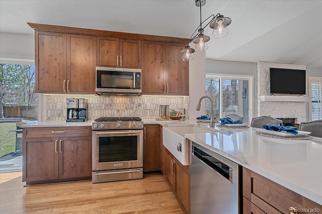 kitchen with open floor plan, light wood-style flooring, a healthy amount of sunlight, and stainless steel appliances