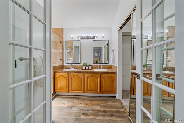 bathroom featuring french doors, wood finished floors, double vanity, and a sink
