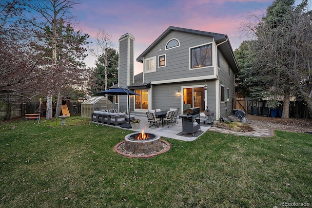rear view of house featuring a yard, an outdoor fire pit, a fenced backyard, and a patio
