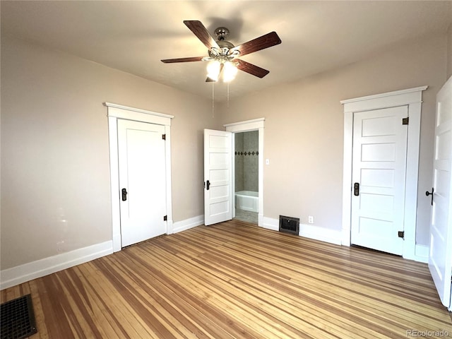 unfurnished bedroom featuring ceiling fan, light wood-type flooring, and connected bathroom