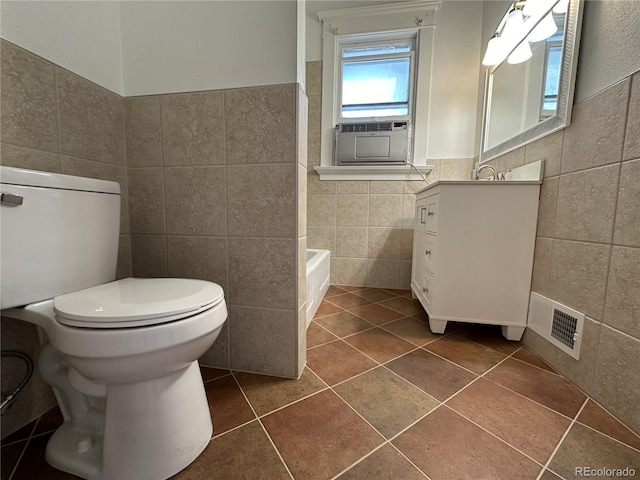 bathroom with a bathing tub, tile patterned flooring, toilet, vanity, and tile walls