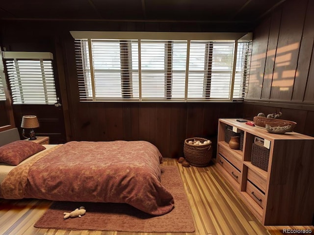 bedroom featuring multiple windows, wood walls, and hardwood / wood-style flooring