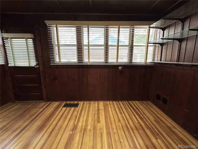 spare room featuring hardwood / wood-style flooring and wood walls