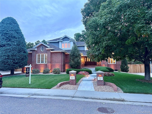 view of front of property featuring fence, a front lawn, and brick siding