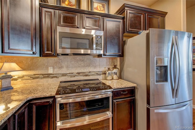 kitchen with stainless steel appliances, backsplash, dark brown cabinets, and light stone countertops