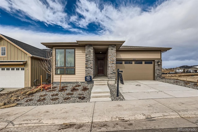 view of front of home featuring a garage, stone siding, board and batten siding, and driveway