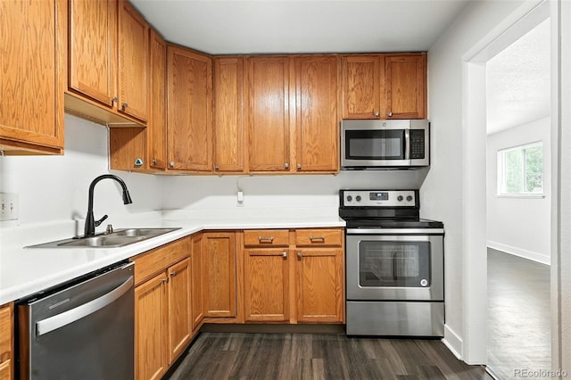 1941 Alton St, Aurora, CO 80010 - kitchen with appliances with stainless steel finishes, light countertops, dark wood finished floors, and brown cabinets