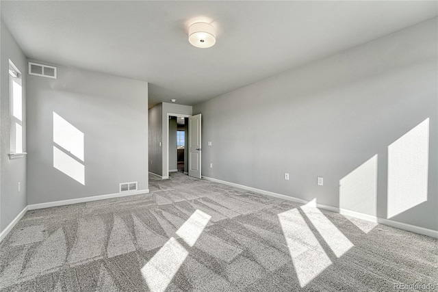 empty room with baseboards, visible vents, and carpet flooring