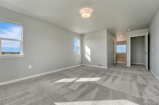 spare room featuring carpet, visible vents, and baseboards