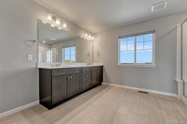 bathroom with double vanity, a sink, visible vents, and baseboards