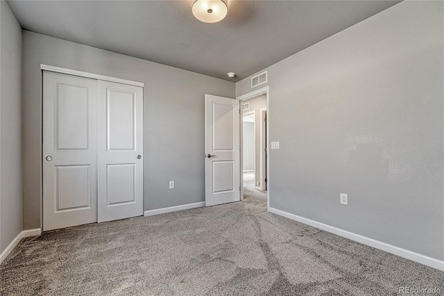 unfurnished bedroom featuring carpet floors, a closet, visible vents, and baseboards