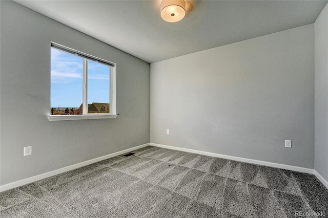 spare room featuring carpet floors, visible vents, and baseboards