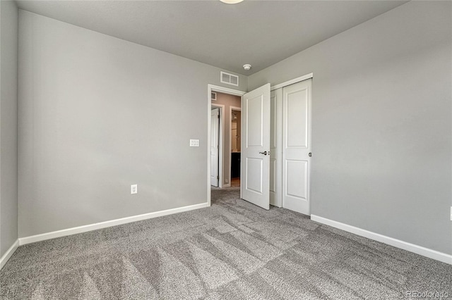 empty room featuring carpet, visible vents, and baseboards