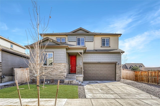 craftsman house featuring concrete driveway, a front yard, fence, a garage, and stone siding