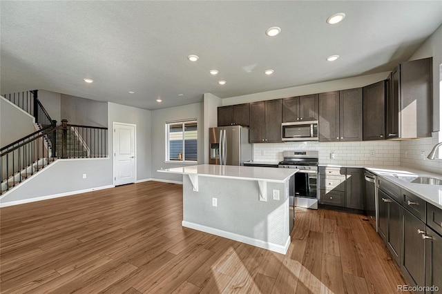 kitchen with a center island, a breakfast bar, stainless steel appliances, decorative backsplash, and dark wood-type flooring