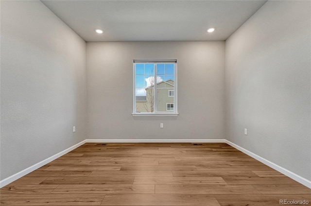 empty room featuring recessed lighting, wood finished floors, and baseboards