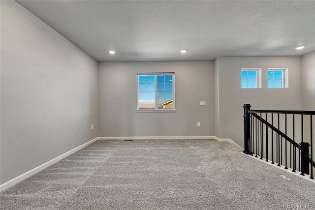 carpeted spare room featuring baseboards, a textured ceiling, recessed lighting, and a healthy amount of sunlight