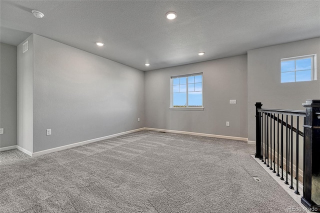 unfurnished room with a textured ceiling, recessed lighting, carpet flooring, and baseboards