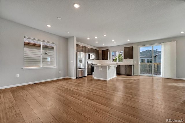 unfurnished living room featuring baseboards, light wood finished floors, and recessed lighting