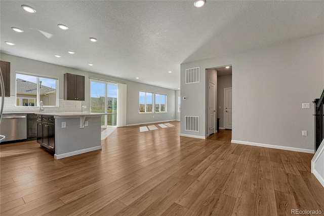 kitchen featuring open floor plan, stainless steel dishwasher, visible vents, and light countertops