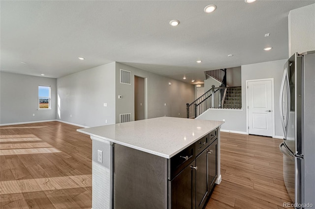 kitchen with visible vents, a center island, freestanding refrigerator, and light wood-style flooring