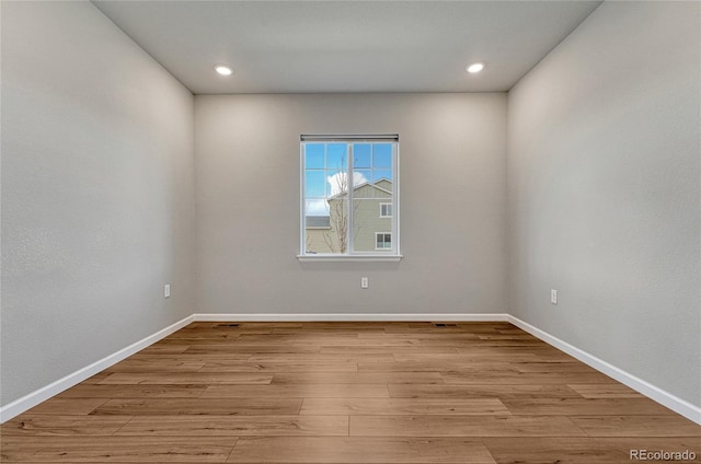 unfurnished room featuring baseboards, wood finished floors, and recessed lighting