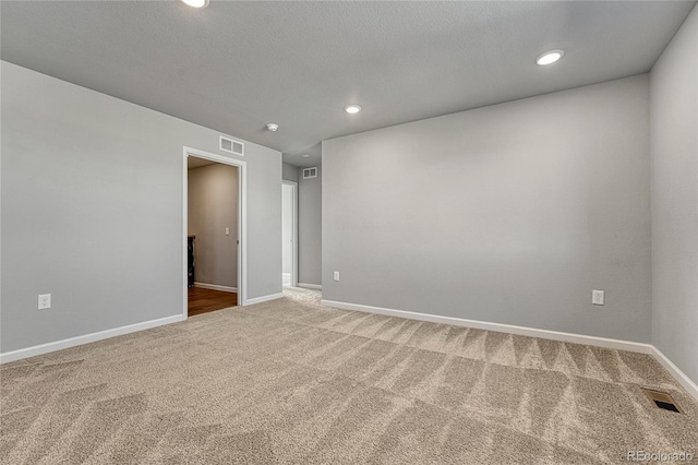carpeted spare room featuring baseboards, visible vents, and recessed lighting