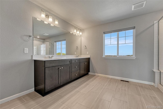 bathroom featuring baseboards, visible vents, a sink, and double vanity