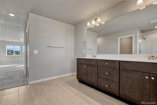 full bath with a sink, double vanity, and a tile shower