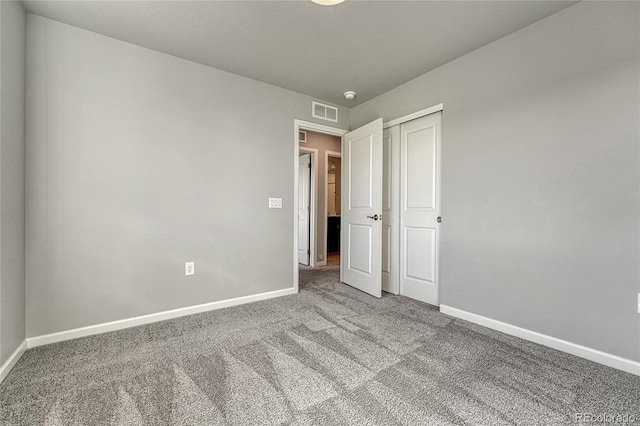 unfurnished bedroom with baseboards, visible vents, carpet floors, and a closet
