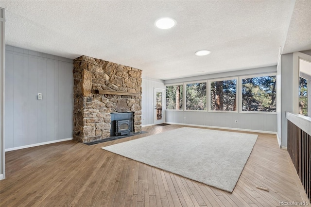 4835 Abo Ln, Monument, CO 80132 - unfurnished living room featuring a textured ceiling, a wood stove, hardwood / wood-style floors, and baseboards