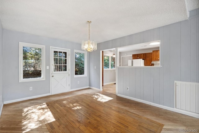 4835 Abo Ln, Monument, CO 80132 - unfurnished dining area with a chandelier, light wood-style floors, a textured ceiling, baseboards, and radiator