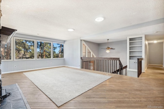 4835 Abo Ln, Monument, CO 80132 - unfurnished living room featuring wood finished floors, a textured ceiling, a ceiling fan, baseboards, and a wood stove