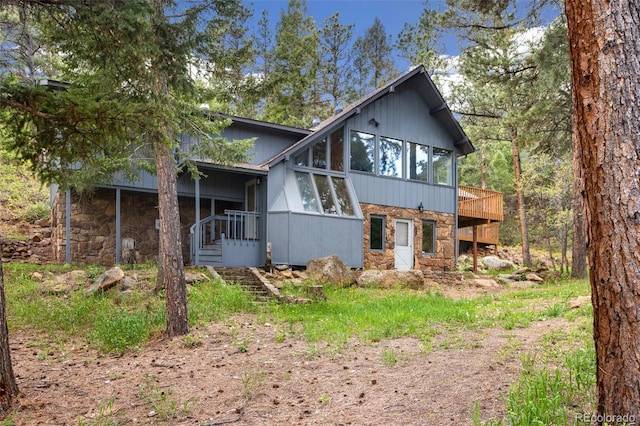 4835 Abo Ln, Monument, CO 80132 - view of front of property featuring stone siding, a sunroom, stairs, and a wooden deck