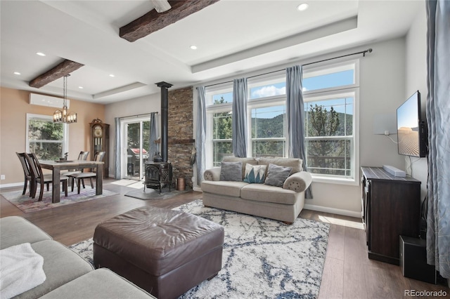 living room with beamed ceiling, a wood stove, a notable chandelier, and dark hardwood / wood-style flooring