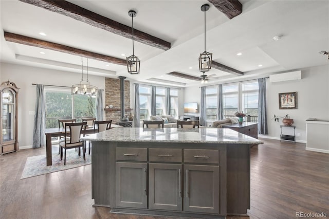 kitchen featuring light stone counters, a wall mounted AC, dark wood-type flooring, and hanging light fixtures