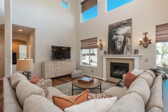 living room with a wealth of natural light, hardwood / wood-style floors, a high ceiling, and a fireplace