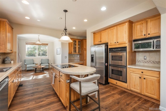 kitchen featuring appliances with stainless steel finishes, dark hardwood / wood-style flooring, pendant lighting, and tasteful backsplash