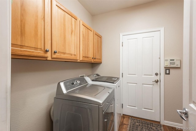 clothes washing area featuring cabinets, washer and dryer, and dark hardwood / wood-style flooring