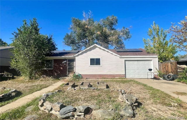 view of front facade with an attached garage, roof mounted solar panels, fence, and driveway