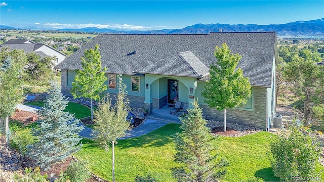 view of front facade with a front yard, a mountain view, a patio, and central AC