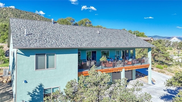 back of house with a mountain view, cooling unit, and a garage