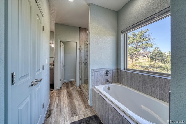 bathroom with hardwood / wood-style flooring and independent shower and bath