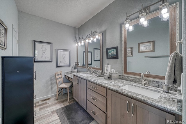 bathroom featuring hardwood / wood-style floors, vanity, and a textured ceiling