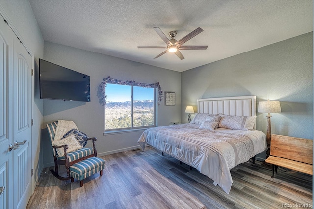 bedroom with a textured ceiling, hardwood / wood-style flooring, a closet, and ceiling fan