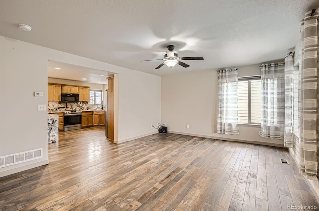 unfurnished living room with hardwood / wood-style flooring, ceiling fan, and a textured ceiling