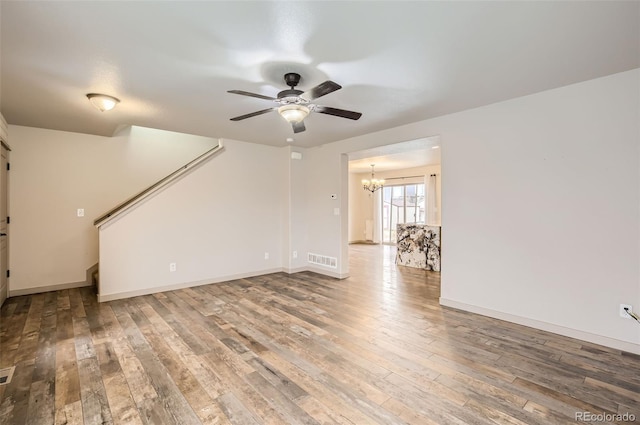 unfurnished living room featuring hardwood / wood-style floors and ceiling fan with notable chandelier