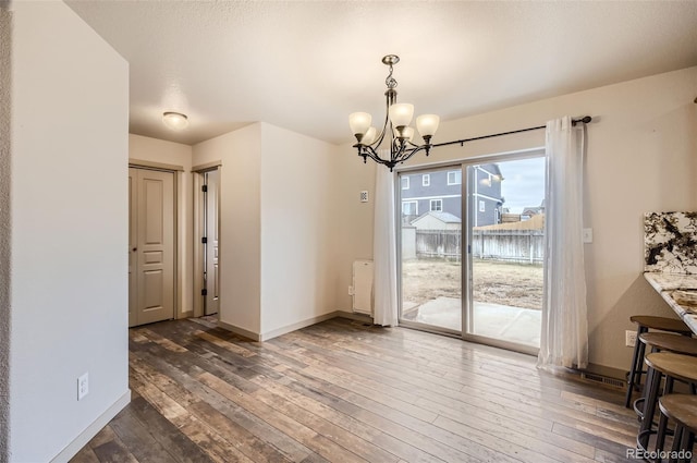 unfurnished dining area featuring an inviting chandelier and dark hardwood / wood-style flooring