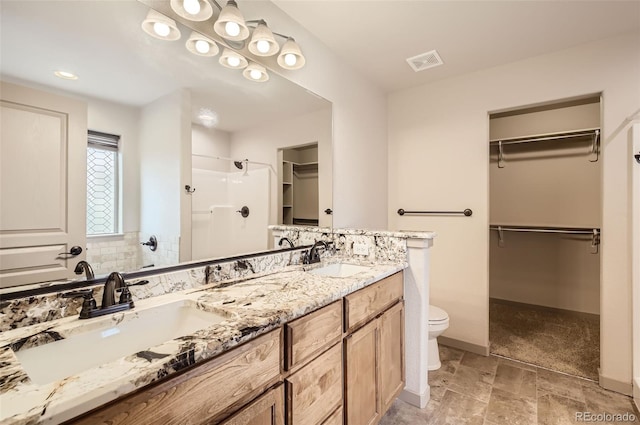 bathroom with walk in shower, vanity, and toilet